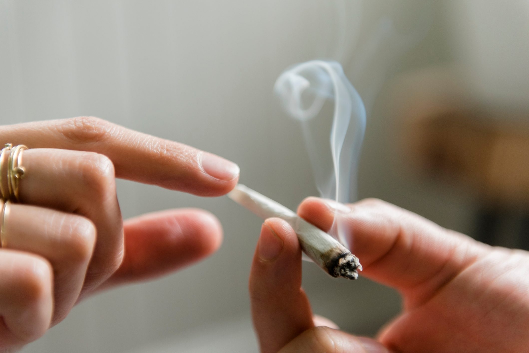 Hands of man and woman passing marijuana joint