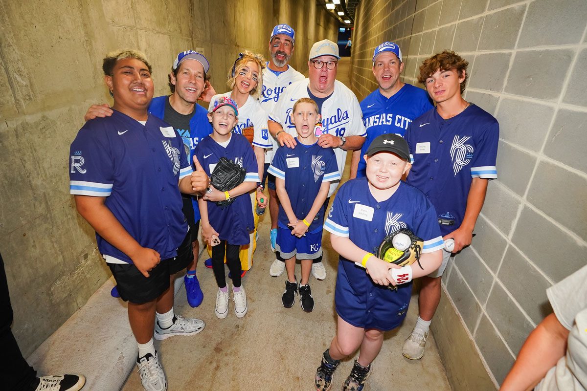 Rob Riggle, Jason Sudeikis, Eric Stonestreet, Heidi Gardner, and Paul Rudd pose for a photo with Childrens Mercy Hospital patients at Kauffman Stadium